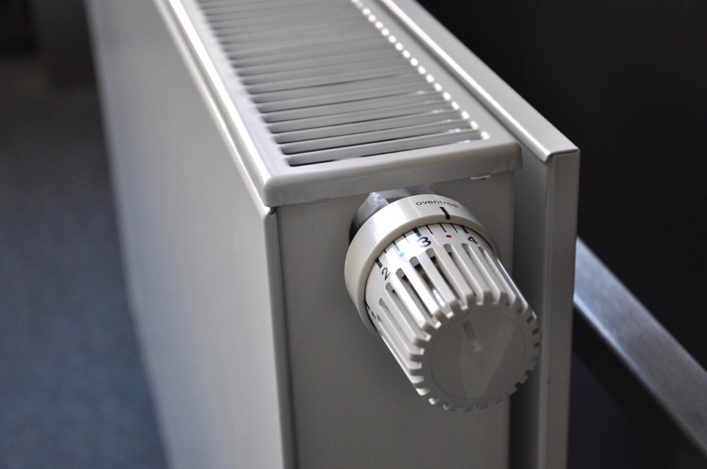 Vit panelradiator monterad under fönster med ny termostatventil – modern installation i bostadsrum för effektiv värmespridning.